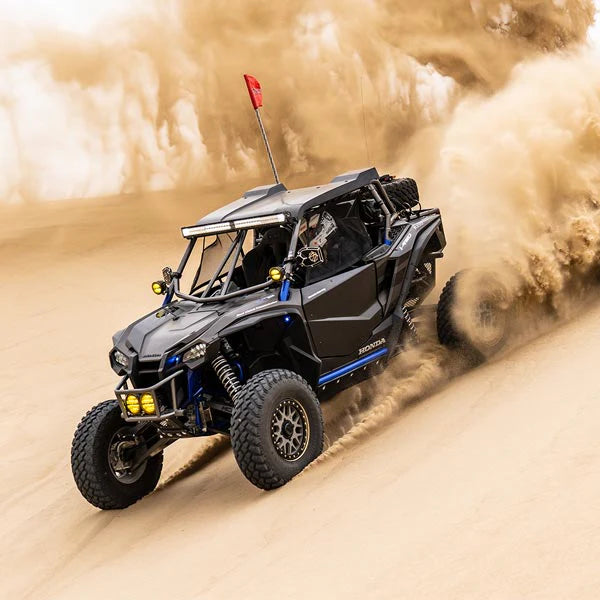 Honda Talon vehicle driving through sand with dust in the air Rugged Radios